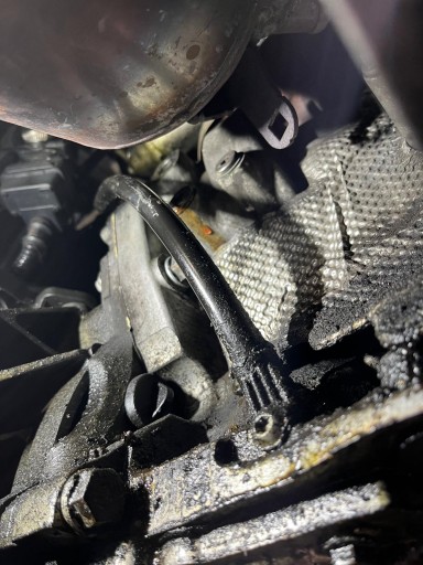 Ter hoogte van de pijlstok aan de achterzijde van het motorblok